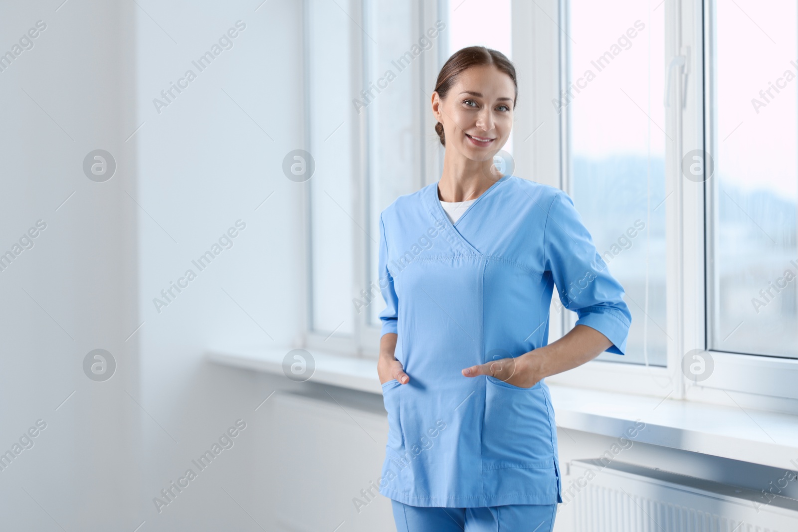 Photo of Nurse in medical uniform near window indoors, space for text