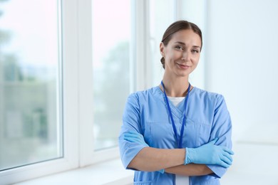 Photo of Nurse in medical uniform near window indoors