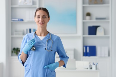 Nurse in medical uniform with stethoscope indoors, space for text