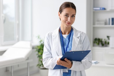 Nurse in medical uniform with clipboard indoors, space for text