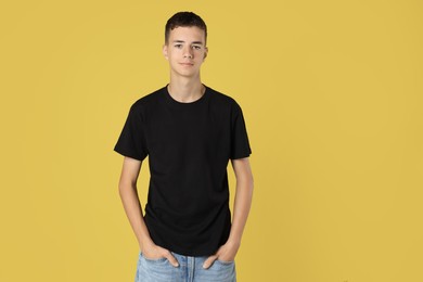 Teenage boy wearing black t-shirt on yellow background