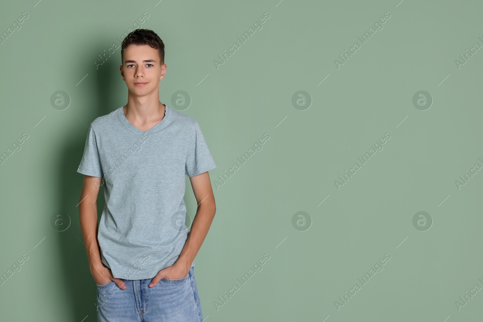 Photo of Teenage boy wearing light grey t-shirt on green background, space for text