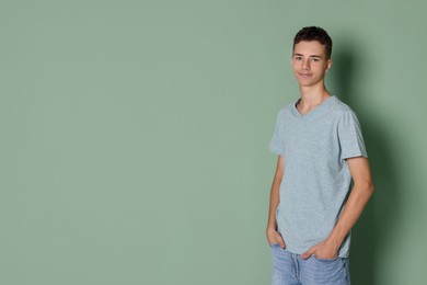 Photo of Teenage boy wearing light grey t-shirt on green background, space for text