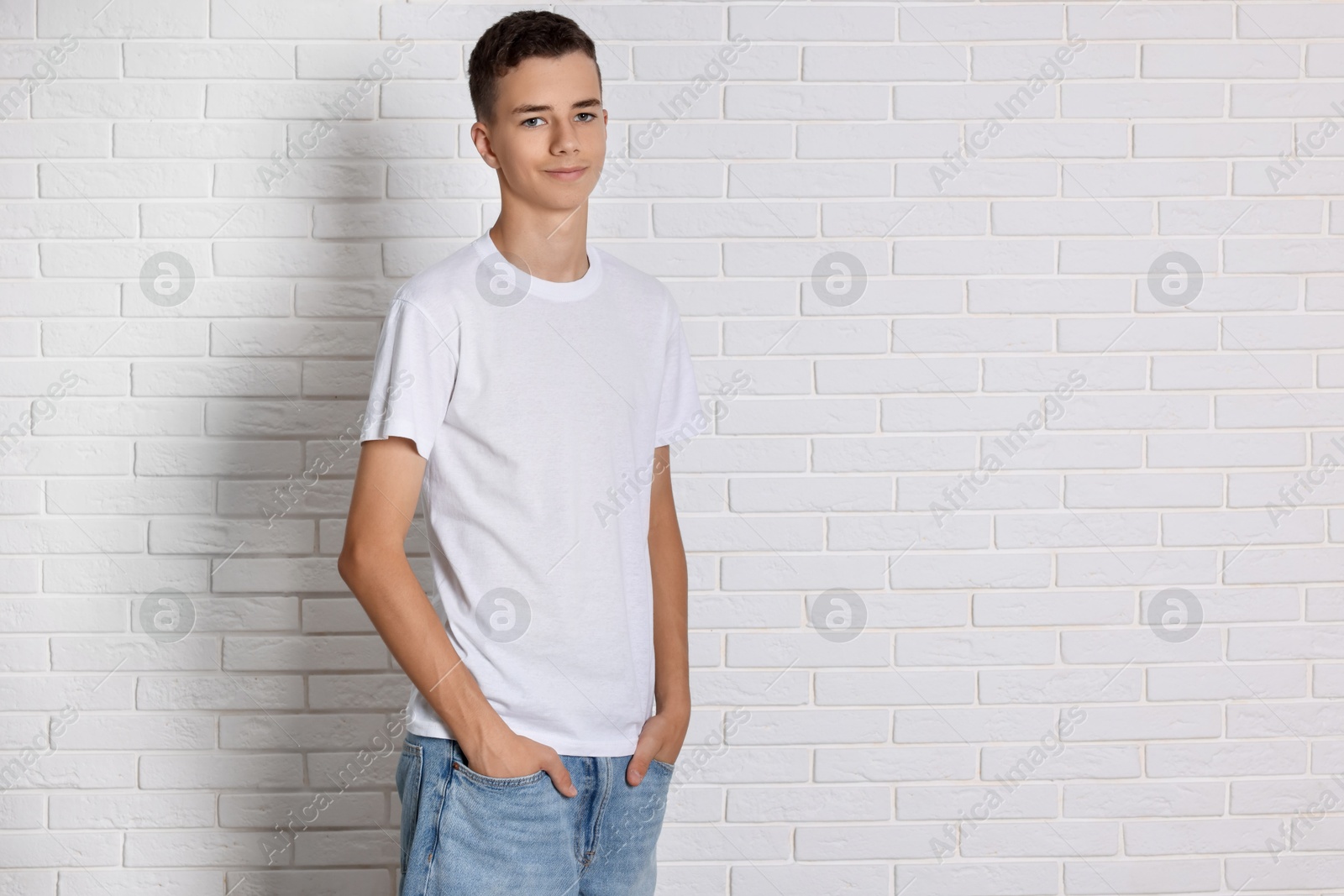 Photo of Teenage boy wearing t-shirt near white brick wall, space for text