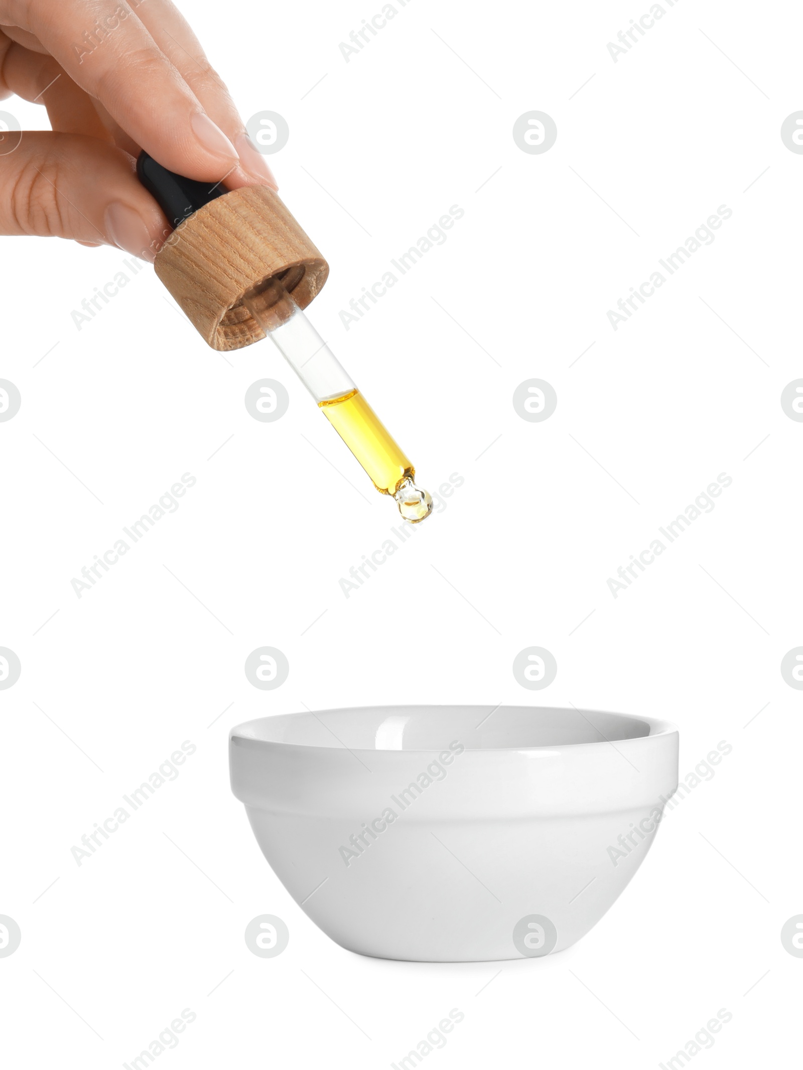 Photo of Woman dripping tincture from pipette into bowl on white background, closeup