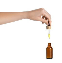 Photo of Woman dripping tincture from pipette into bottle on white background, closeup