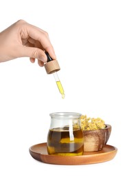 Photo of Woman dripping tincture from pipette into glass jar on white background, closeup