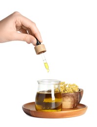 Photo of Woman dripping tincture from pipette into glass jar on white background, closeup