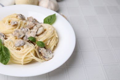 Photo of Delicious pasta with mushrooms and basil on white tiled table, closeup. Space for text