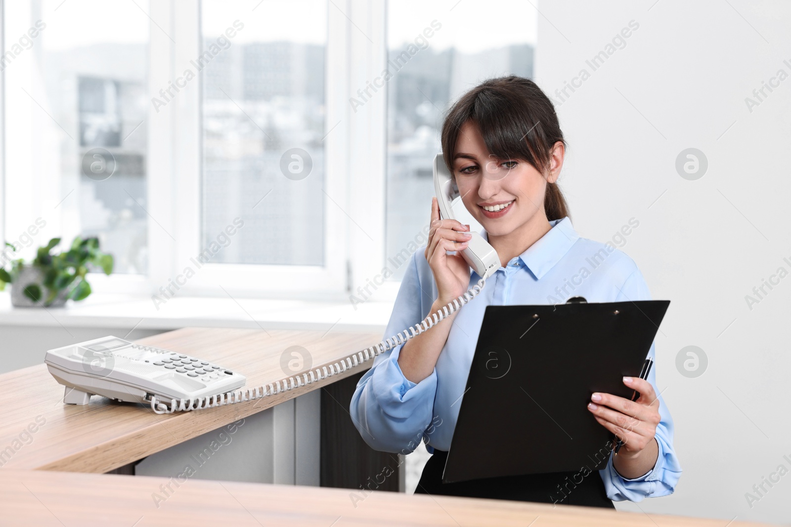 Photo of Professional receptionist talking on phone in office