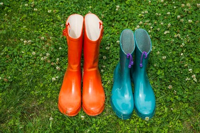 Two pairs of rubber boots on green grass outdoors