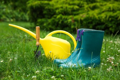 Rubber boots and gardening tools on green grass outdoors