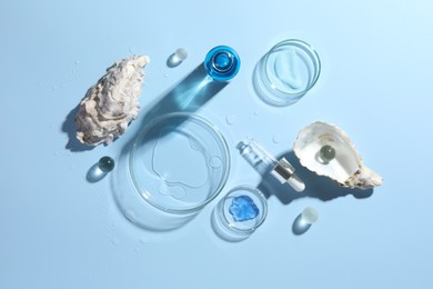 Petri dishes with cosmetic product, pipette and seashells on light blue background, flat lay