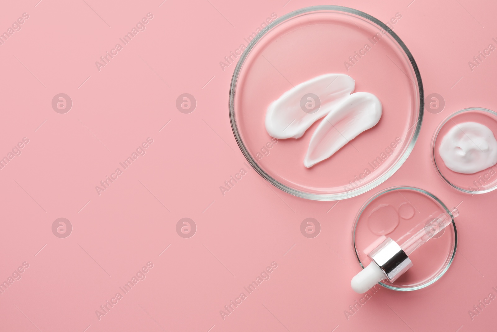 Photo of Petri dishes with cosmetic products and pipette on pink background, flat lay. Space for text