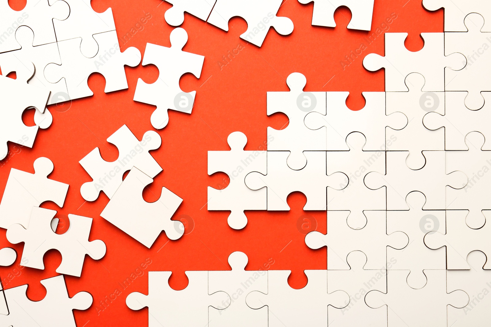 Photo of White puzzle pieces on red background, top view