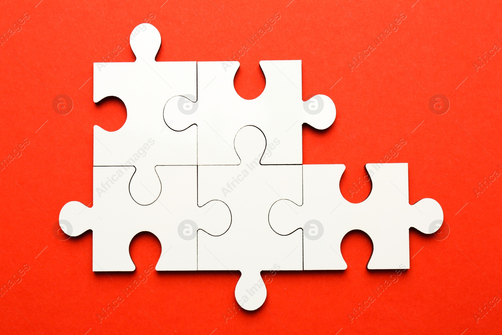 Photo of White puzzle pieces on red background, top view