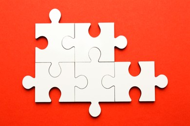 Photo of White puzzle pieces on red background, top view