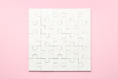 White puzzle on pink background, top view