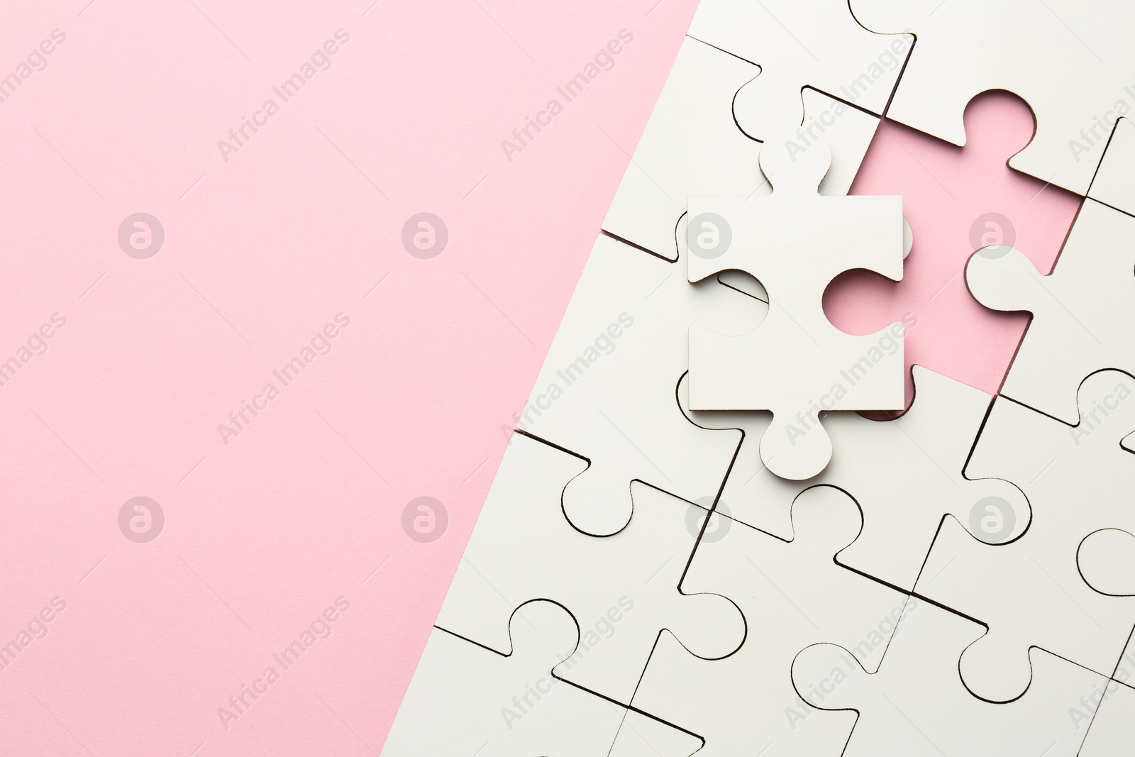 Photo of White puzzle pieces on pink background, top view. Space for text