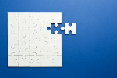 Photo of White puzzle pieces on blue background, top view