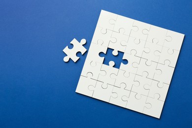 White puzzle pieces on blue background, top view