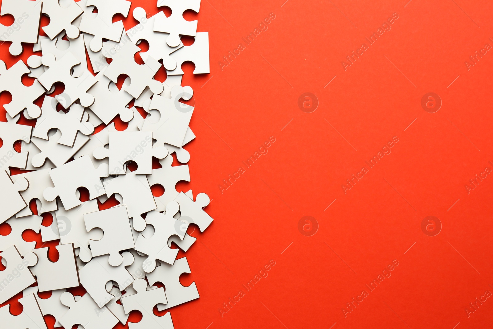 Photo of White puzzle pieces on red background, top view. Space for text