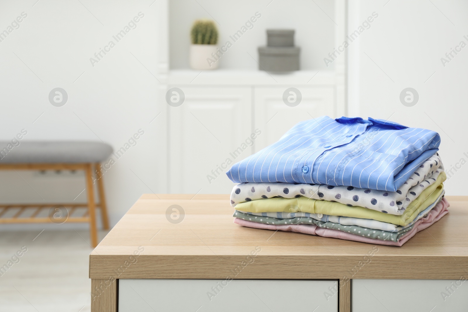 Photo of Stack of clean clothes on wooden dresser indoors