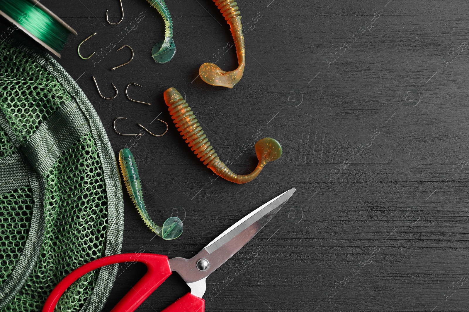 Photo of Fishing baits, hooks, net, line and scissors on grey wooden table, flat lay. Space for text