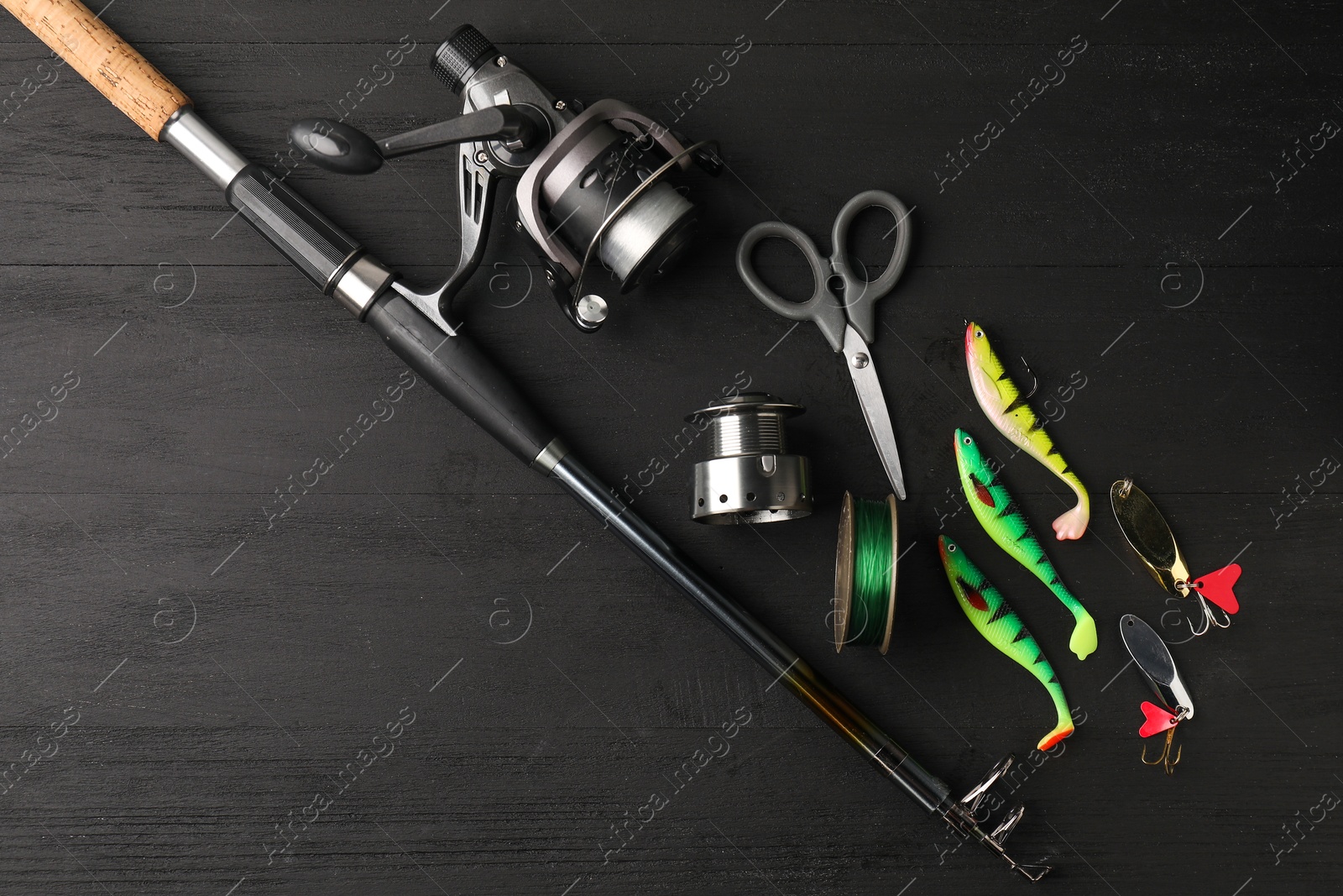 Photo of Fishing rod with spinning reel, line, baits and scissors on grey wooden table, flat lay