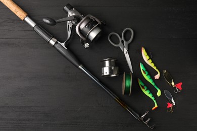 Fishing rod with spinning reel, line, baits and scissors on grey wooden table, flat lay