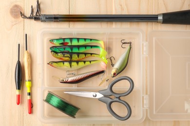 Photo of Fishing rod, baits, floats, scissors and line on wooden table, top view