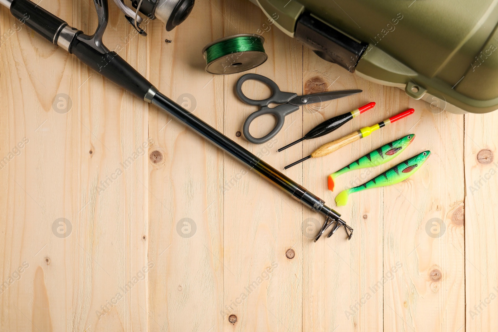 Photo of Fishing rod with spinning reel, baits, scissors, line and tackle box on wooden table, top view. Space for text