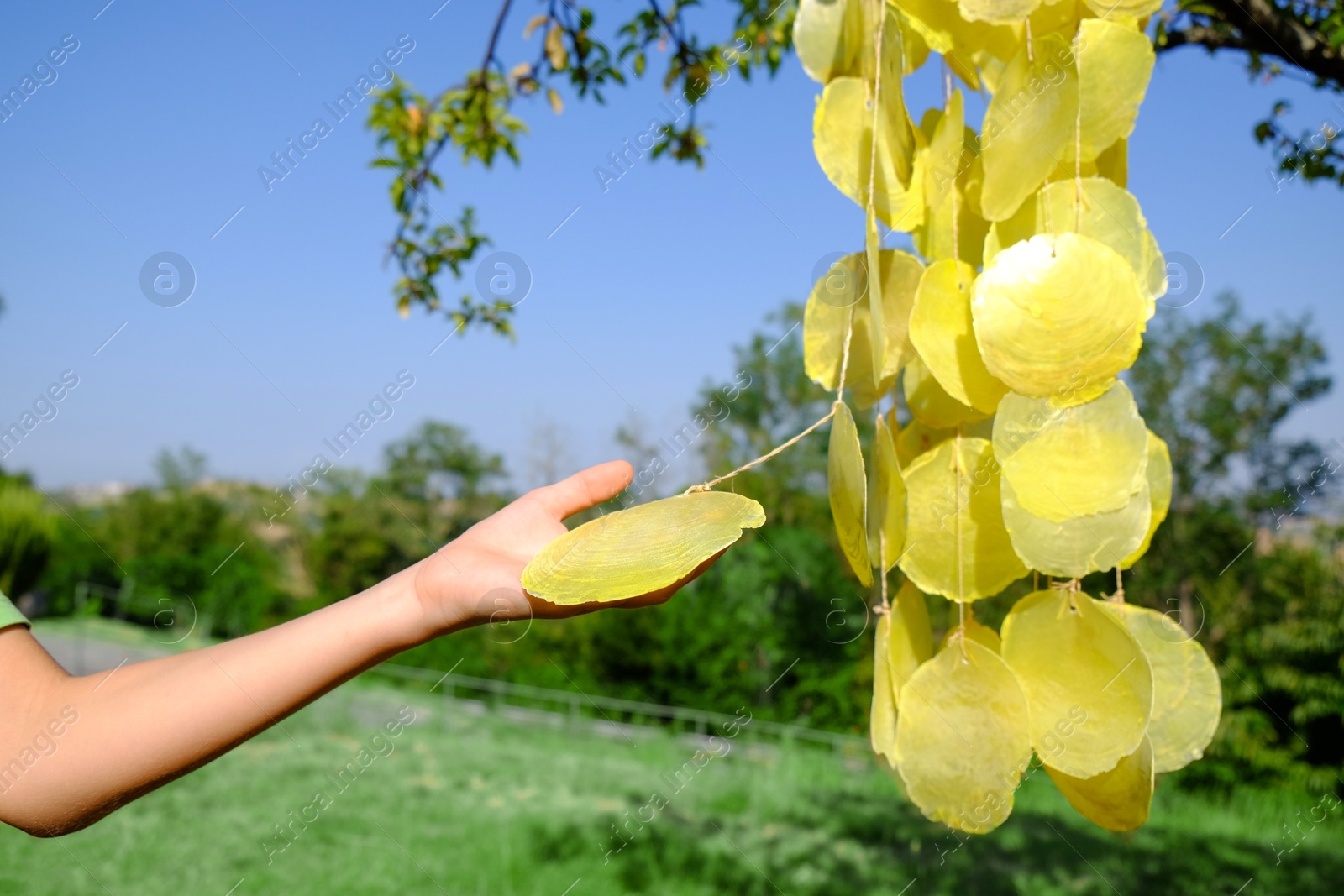 Photo of Woman enjoying beautiful wind chimes outdoors, closeup