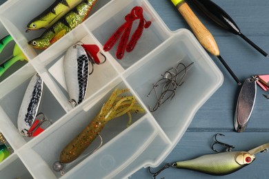 Different fishing baits, hooks and floats on blue wooden table, top view