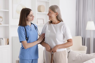 Young healthcare worker supporting senior patient indoors