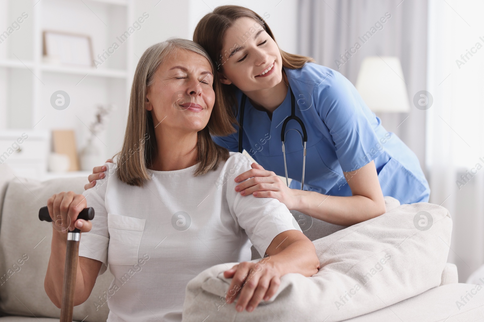 Photo of Smiling healthcare worker supporting senior patient indoors