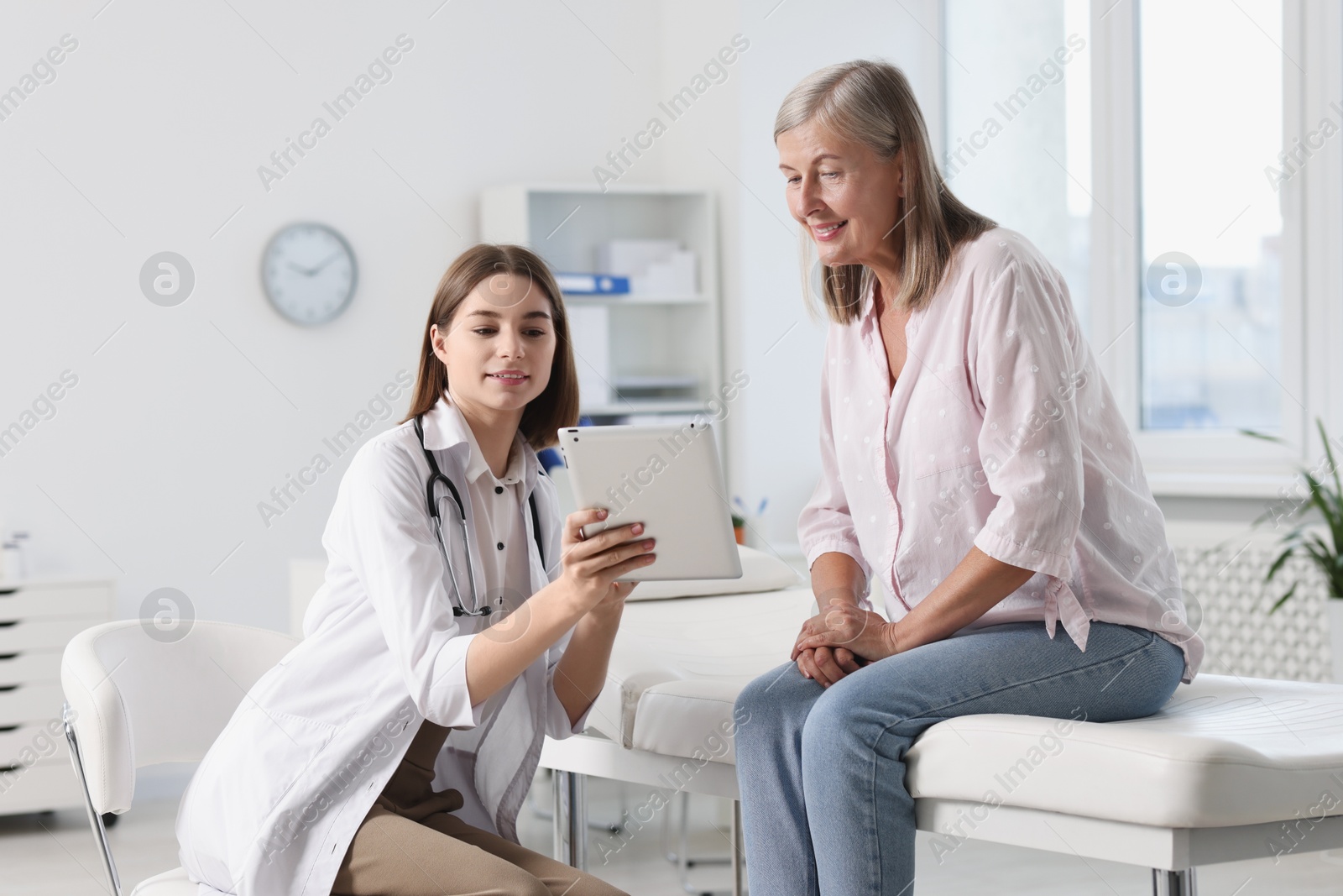 Photo of Smiling healthcare worker and senior patient checking analysis results on tablet in hospital