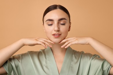 Photo of Face massage. Beautiful young woman with healthy skin on beige background