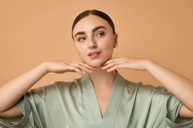 Photo of Face massage. Beautiful young woman with healthy skin on beige background