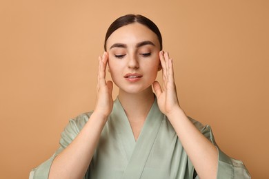 Photo of Face massage. Beautiful young woman with healthy skin on beige background