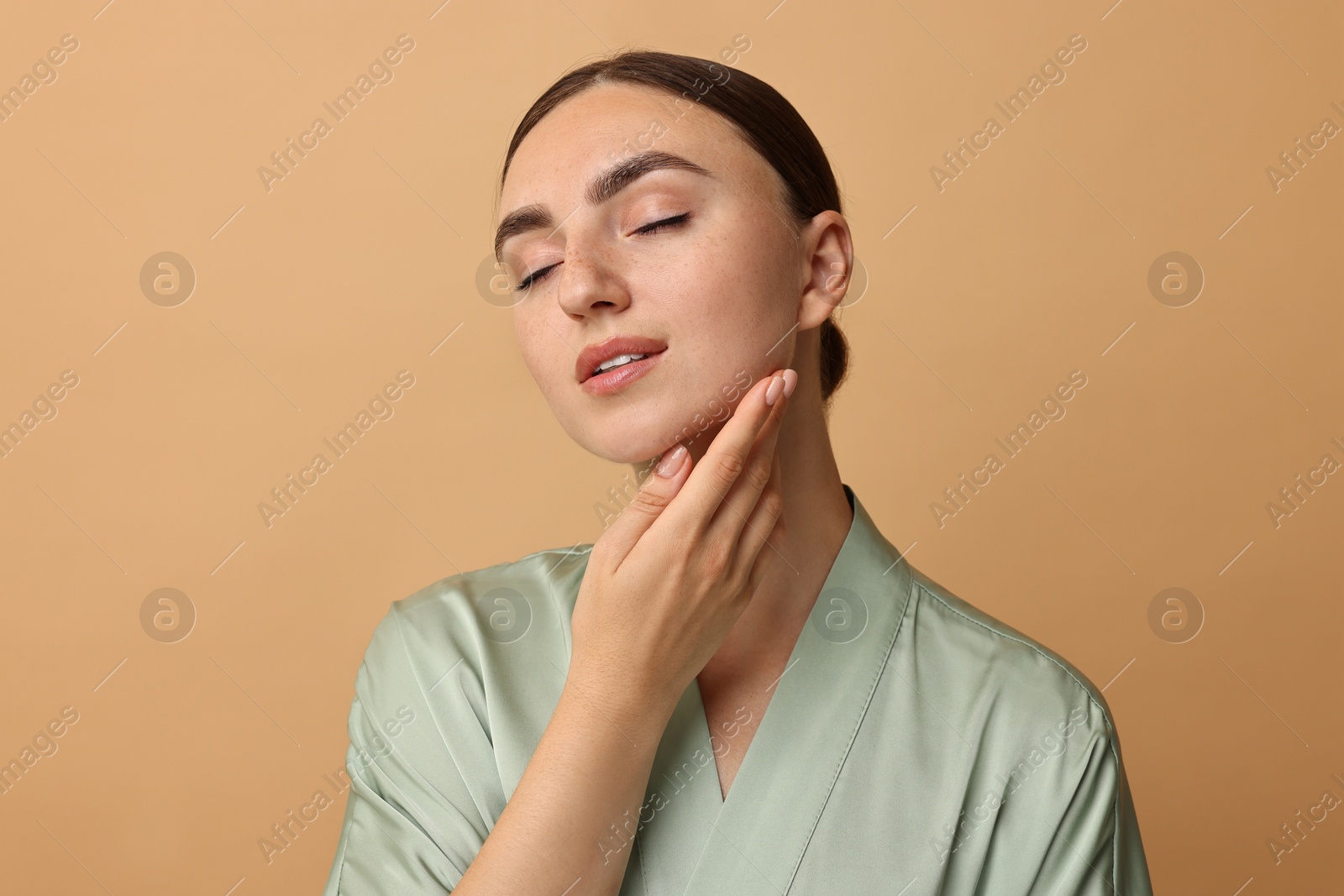 Photo of Face massage. Beautiful young woman with healthy skin on beige background