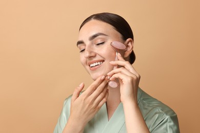 Photo of Beautiful young woman doing facial massage with roller on beige background