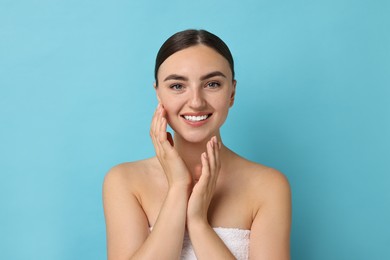 Beautiful young woman with healthy skin on light blue background