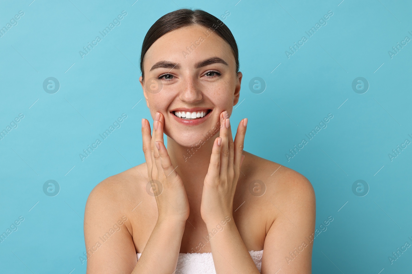 Photo of Face massage. Beautiful young woman with healthy skin on light blue background