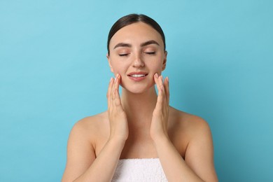 Photo of Face massage. Beautiful young woman with healthy skin on light blue background