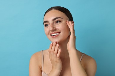 Photo of Face massage. Beautiful young woman with healthy skin on light blue background