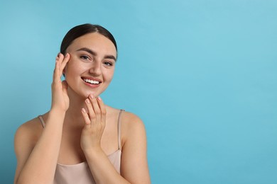 Photo of Face massage. Beautiful young woman with healthy skin on light blue background, space for text