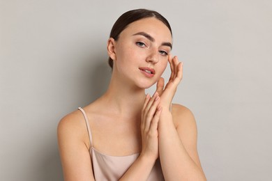 Beautiful young woman with healthy skin on grey background