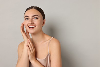 Photo of Beautiful young woman with healthy skin on grey background, space for text