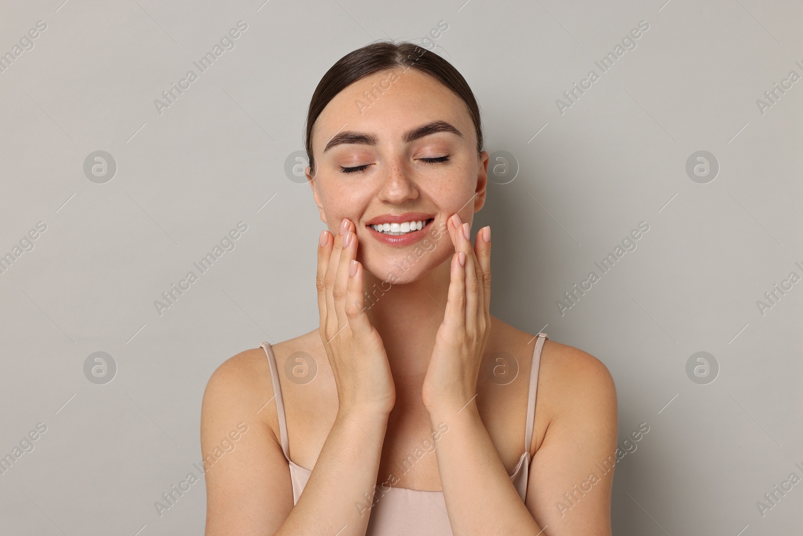 Photo of Face massage. Beautiful young woman with healthy skin on grey background